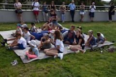 Goście biorący udział w warsztatach, siedzący na dywanie na zielonym dachu Parku Nauki Torus.